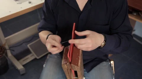 In the workshop, a man is sewing leather workpieces, making a wallet Stock Footage 88839544