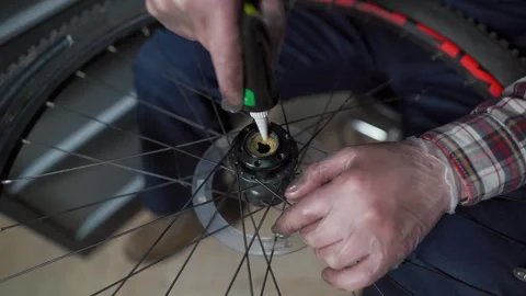 In a workshop, a mechanic in workwear repairs a mountain bike, focusing on hub Stock Footage 327928134