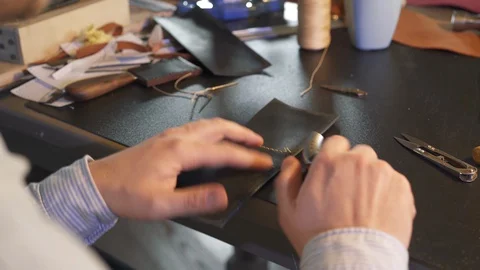Workshop owner works in workplace. Young leather craftsman creates a DIY product Stock Footage 130146572