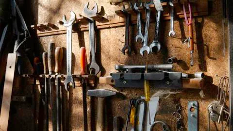 Workshop scene. Tools on the board. Old tools hanging on wall in workshop. Stock Photos
