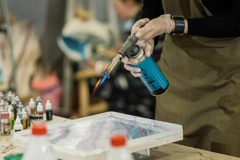 At the workshop, sealed hands work with a gas burner, creating a picture of  Stock Photos
