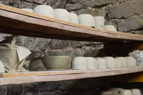 Workshop shows various clay items arranged on wooden shelves in a pottery studio Stock Photos