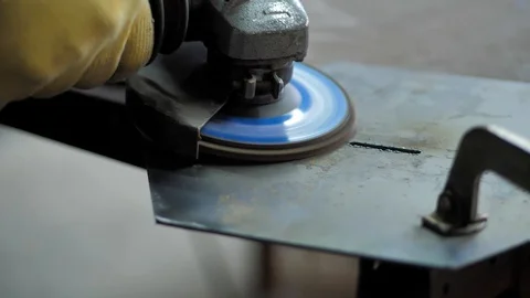 In the workshop. Slow motion. The man grinds a metal part with an Angle grinder Stock Footage 128998156