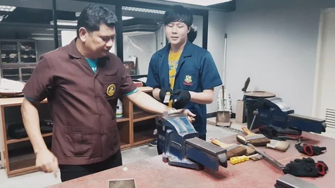 Workshop teacher teaching a student how to use tools to hand file a metal Video stock 102570532