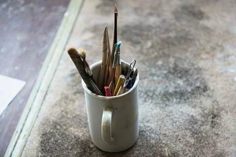 In workshop there are a lot of different tools for handicrafts in cups. Stock Photos