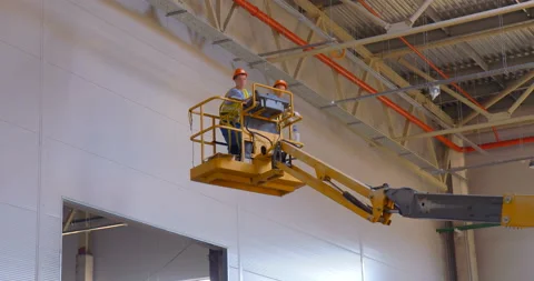 In a workshop under construction, car lifts raise workers in their cradle  Stock Footage 161984434