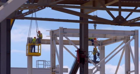 In a workshop under construction, car lifts raise workers in their cradle Stock Footage 161984953