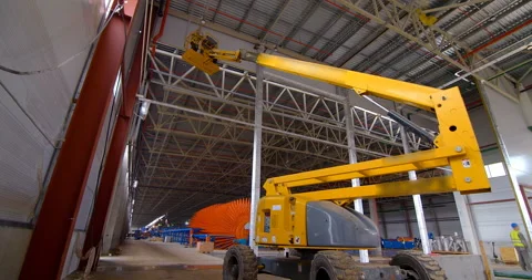 In a workshop under construction, car lifts raise workers in their cradle Stock Footage 161990352