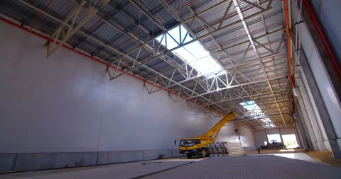 In a workshop under construction, a powerful yellow truck crane unload beams Stock Footage 161983596