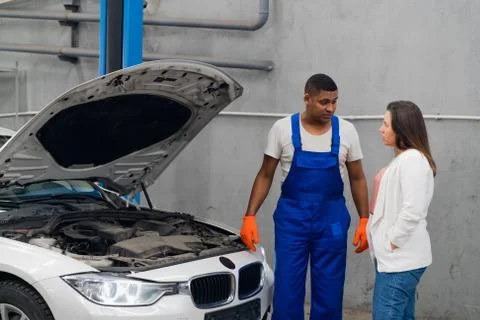 Workshop worker and customer inspect engine of car Stock Photos