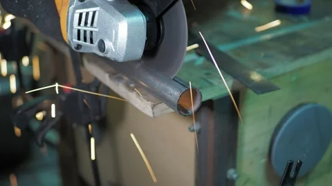 Workshop. A worker uses a angle grinder to cut a steel pipe. Video stock 311759885