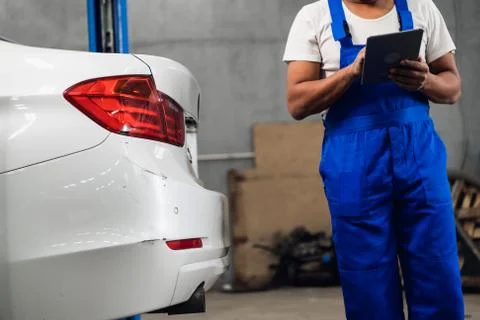 A workshop worker writes report about a car on clipboard Stock Photos