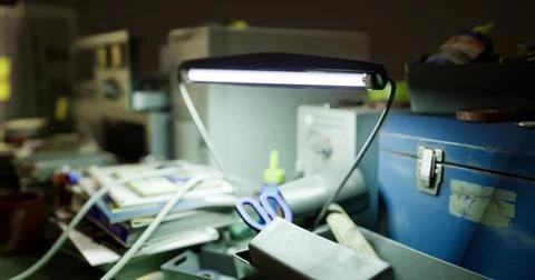 Workspace clutter with lamp illuminating scattered papers and tools Stock Illustration