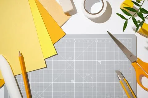 Workspace with cutting mat, scissors, cutter, yellow paper and stationery o.. Stock Photos
