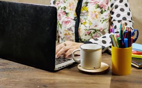 A workspace featuring hands typing on a keyboard surrounded by colorful office s Stock Photos