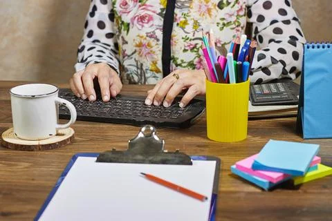 A workspace featuring hands typing on a keyboard surrounded by colorful office  Stock Photos