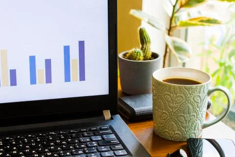 Workspace at home, notebook, mobile device, coffee and plants on the table Stock Photos