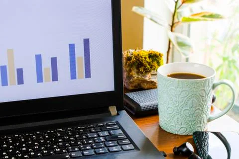Workspace at home, notebook, mobile device, coffee and plants on the table Stock Photos