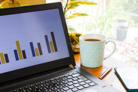Workspace at home, notebook, mobile device, coffee and plants on the table Stock Photos