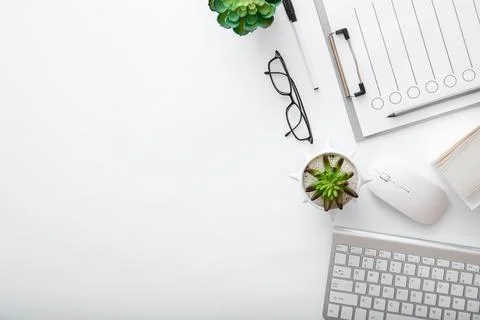 Workspace with keyboard mouse glasses papers green plants. Flat lay White desk Foto stock