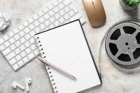 Workspace with notebook, keyboard, mouse, and film reel Stock Photos