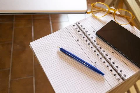 Workspace with notebook, pen, smartphone, glasses for remote work Stock Photos