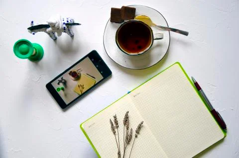 Workspace with notepad, cup of tea on a white background. Flat lay, top view Stock Photos