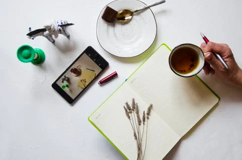 Workspace with notepad, cup of tea on a white background. Flat lay, top view Stock Photos