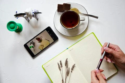 Workspace with notepad, cup of tea on a white background. Flat lay, top view Stock Photos