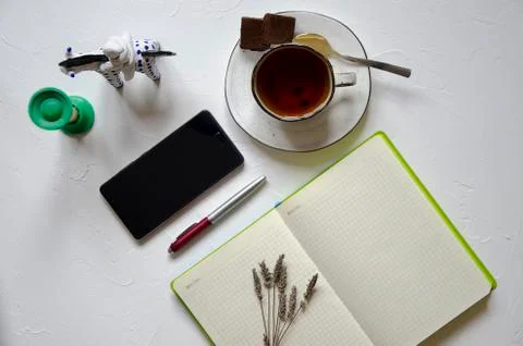 Workspace with notepad, cup of tea on a white background. Flat lay, top view Stock Photos