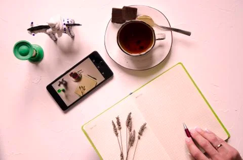 Workspace with notepad, cup of tea on a white background. Flat lay, top view Stock Photos