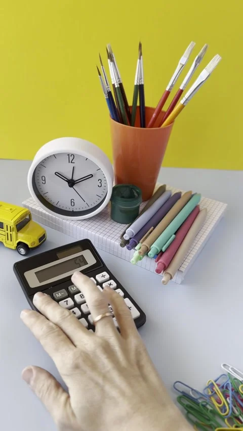 Workspace scene featuring calculator, clock, colorful pens, stationery item.. Stock Footage 309397128