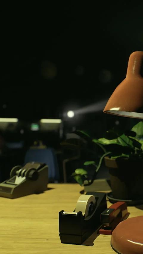 Workspace setup with lamp, tape dispensers, and a plant on the desk at night Stock Footage 332231906
