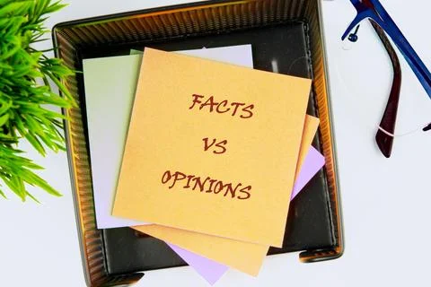 A workspace shows notes on facts and opinions stacked in an organizer. There  写真素材