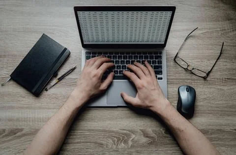 Workspace on the table. Hands typing on a laptop keyboard. Black notebook Stock-Fotos