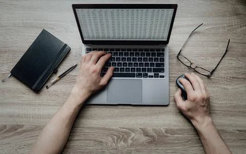 Workspace on the table. Hands typing on a laptop keyboard. Black notebook 写真素材