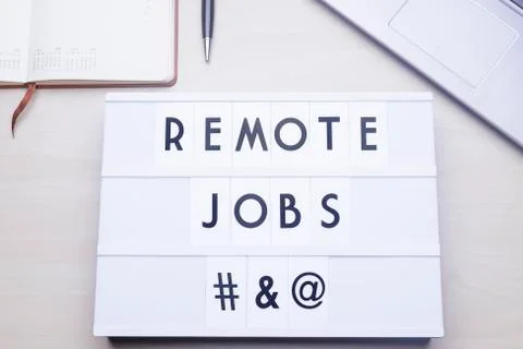 Workspace table with a lichtbox with the words REMOTE JOBS. Stock Photos