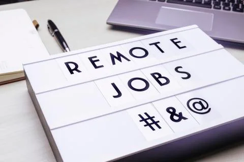 Workspace table with a lichtbox with the words REMOTE JOBS. Stock Photos