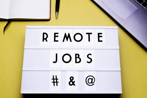 Workspace table with a lichtbox with the words REMOTE JOBS. Stock Photos