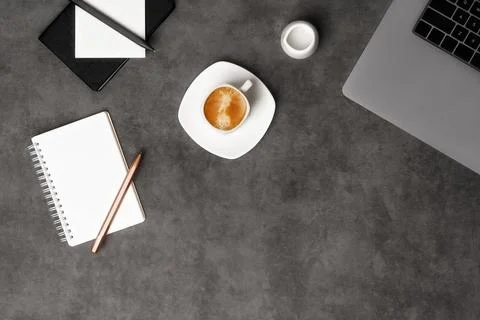 Workspace top view with laptop, notepad, pens and coffee on dark grey stone Stock Photos