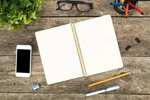Workspace on a wooden table featuring a blank notebook, smartphone, and Stock Photos