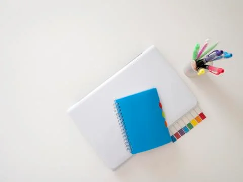 Worktable with closed laptop, notepad and color markers. Top view Foto stock