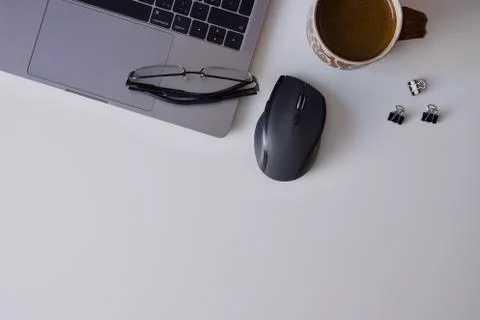 Worktable with laptop, mouse, glasses, mug of black coffee and pen, copy space Stock Photos