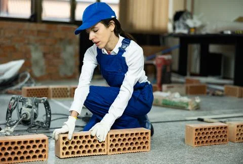 Workwoman preparing bricks for masonry at construction site indoors Foto stock