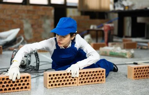 Workwoman preparing bricks for masonry at construction site indoors Foto stock