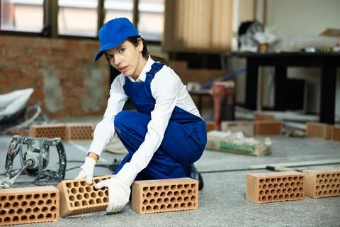 Workwoman preparing bricks for masonry at construction site indoors Foto stock