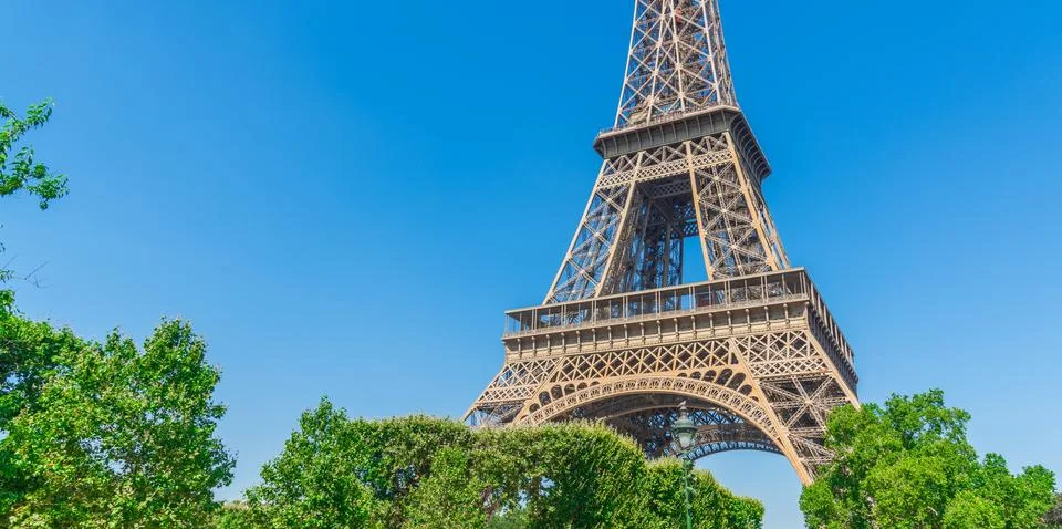 World famous Eiffel tower behind green trees under a blue sky Fotos de archivo