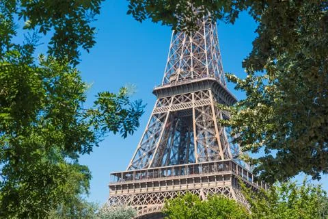 World famous Eiffel tower seen through green trees in Paris Stock Photos
