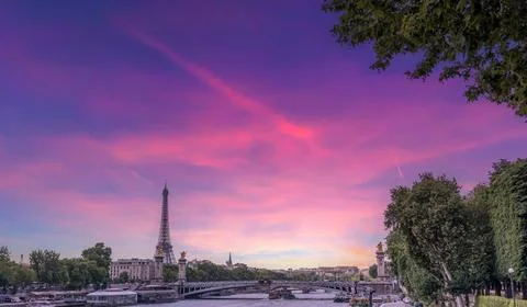 World famous Eiffel tower by Seine river under a pink sky at sunset Stock Photos