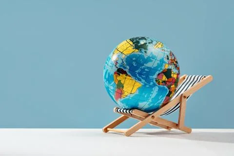 World globe resting on sun bed chair. Earth day taking break Stock Photos